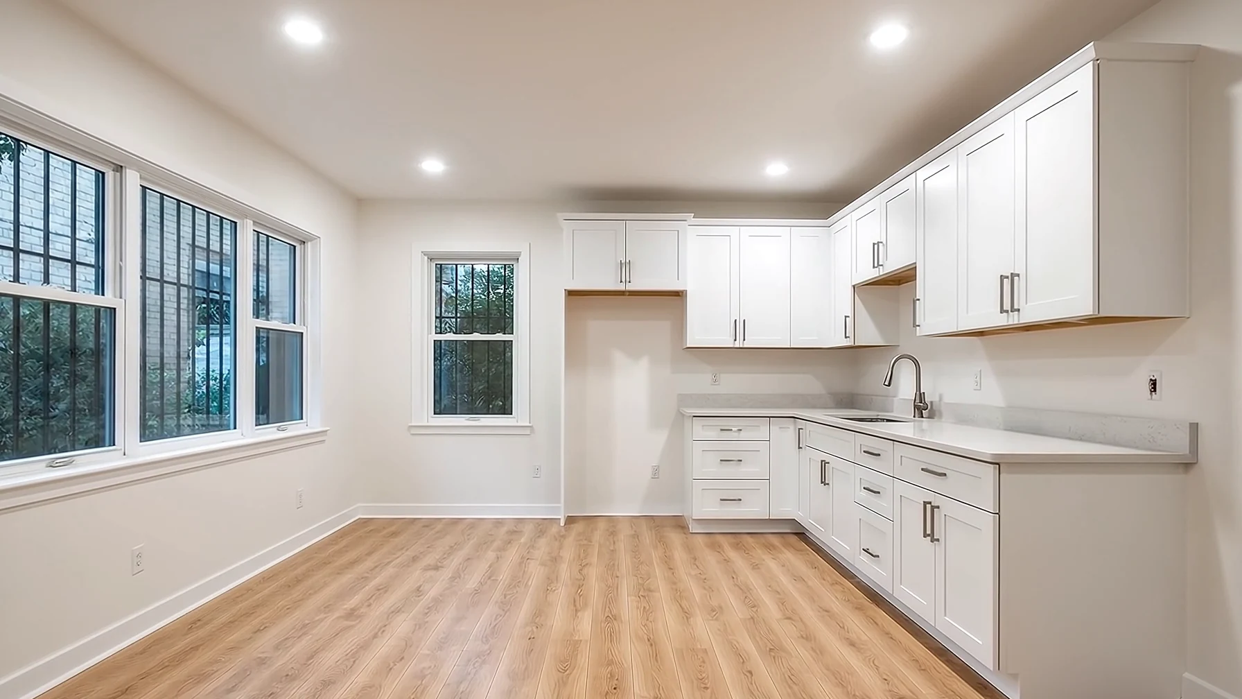 A renovated open kitchen with an oak island, white walls and wide windows onto the garden