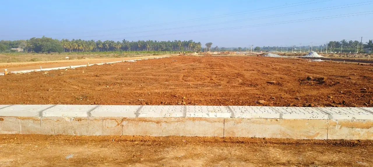 A line of concrete kerb with levelled red-earth plots behind it