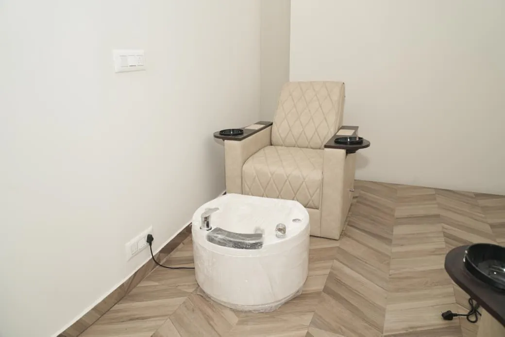 Pedicure station: a quilted cream armchair with a foot basin on the herringbone floor