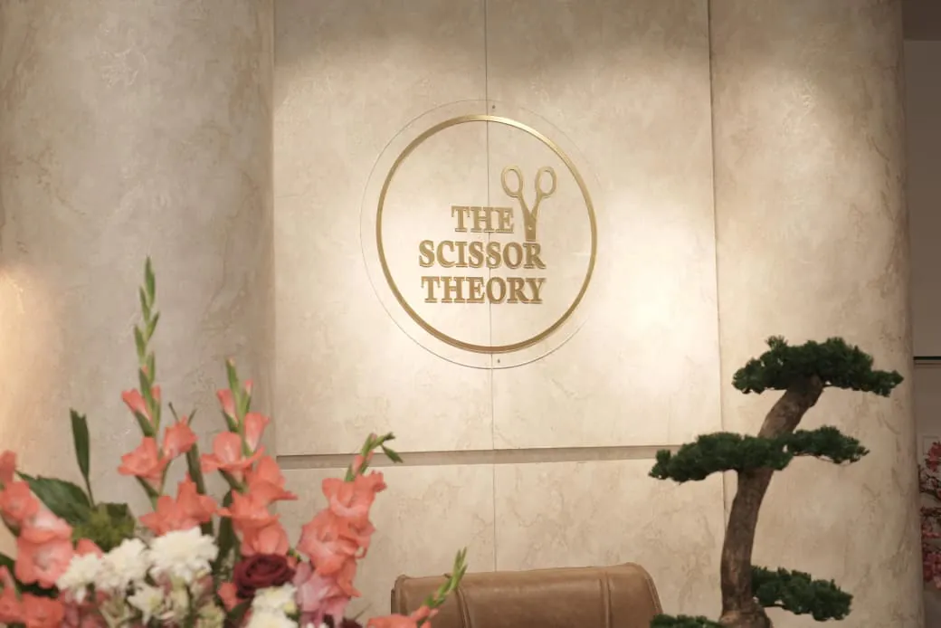 Close view of the reception wall: the gold salon sign mounted on cream textured panels