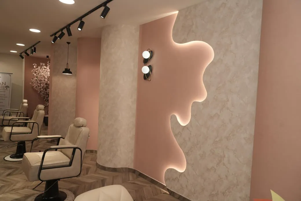Styling chairs beside a rounded column and a wave-edged wall panel lit from behind