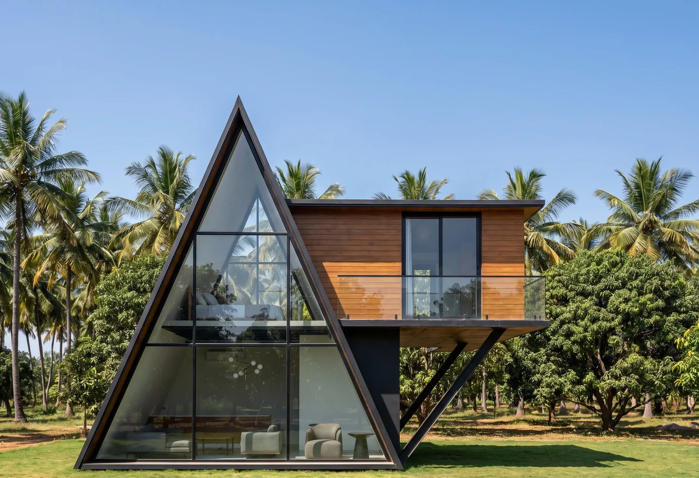 A glass-fronted A-frame with a timber-clad cabin cantilevered out of its side on steel struts