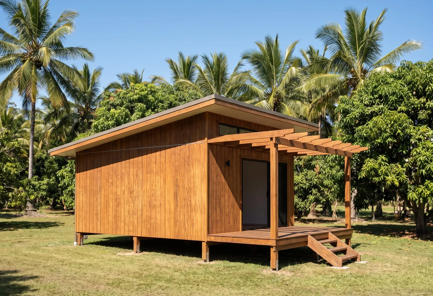 A timber-clad studio cottage with a pergola-covered deck and steps up to it