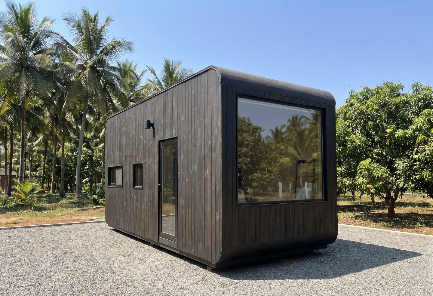 A compact dark timber cabin with rounded corners and one very large window
